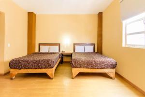 two beds in a room with a desk and a window at Capital O Hotel Del Parque Guadalajara in Guadalajara