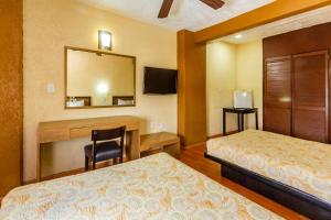 a bedroom with two beds and a desk and a mirror at Capital O Hotel Del Parque Guadalajara in Guadalajara