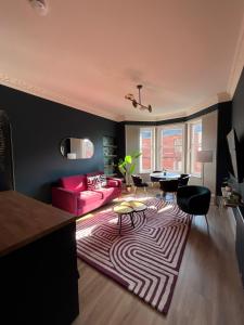 a living room with a pink couch and a rug at Townhead Jewel by Coorie Doon Stays in Paisley