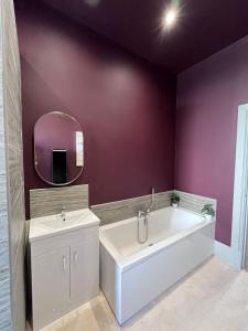 a bathroom with a white tub and a sink at Townhead Jewel by Coorie Doon Stays in Paisley