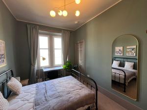 a bedroom with a large bed and a mirror at Townhead Jewel by Coorie Doon Stays in Paisley