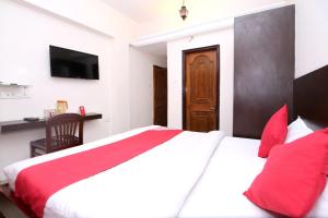 a bedroom with a large bed with red pillows at Hotel O Dwarika Inn in Jabalpur