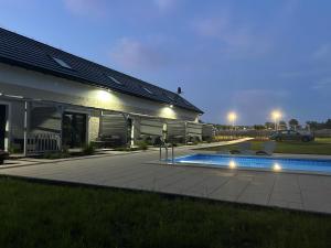 a house with a swimming pool next to a building at Mamma Mia Park in Łukęcin