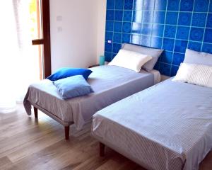 two beds in a room with blue tiles on the wall at B&B La Casa Bianca di Porto Conte in Porto Conte