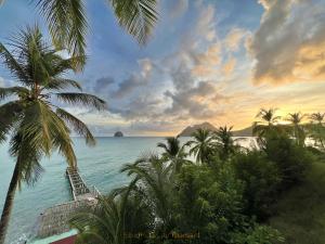 Una vista del océano desde un resort con palmeras. en Studio Or au Diamant, vue mer des Caraïbes, en Le Diamant