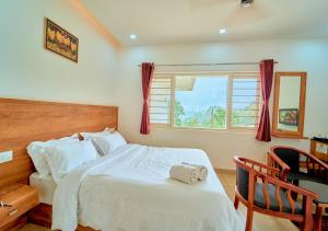 Un dormitorio con una gran cama blanca con ventana. en Munnar Ice Pellets Resort with Pool by VOYE HOMES, en Munnar