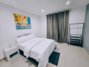 a white bedroom with a bed and a window at Bilene Harmony Home in Vila Praia Do Bilene