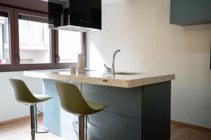 a kitchen with two chairs and a sink and a counter at Apartamento Vermú in Guadix