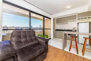 a living room with a couch and a kitchen at Green Center - Centro de Curitiba - 1 quarto in Curitiba