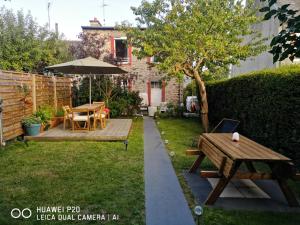 a garden with a wooden table and an umbrella at chambres dans Maison individuelle 46 Rue de Luzel in Saint-Brieuc