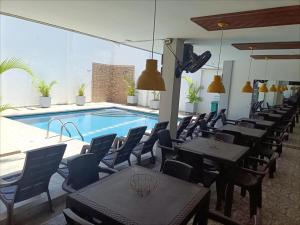 a restaurant with tables and chairs next to a swimming pool at Hotel Velero Guajira Real in Fonseca