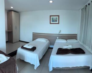 a hotel room with two beds with towels on them at Colorado Hotel in Eunápolis +12 photos