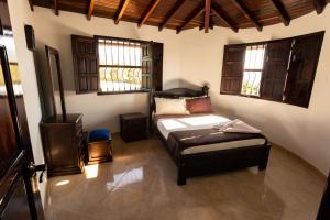 a bedroom with a bed in a room with windows at Condominio Parque Baviera in Barichara +121 photos