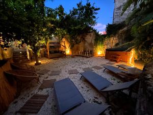 a courtyard with lounge chairs and trees at night at Rada room&suite in Favignana