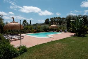 een zwembad met stoelen en parasols in een tuin bij Cas Colector in Selva
