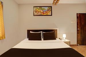 a bedroom with a large white bed and a picture on the wall at Super Townhouse Vaishnavi in Hyderabad +26 photos