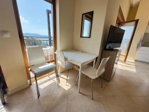 a room with a table and chairs and a television at Santa Marina resort Sozopol - penthouse with amazing sea view in Sozopol