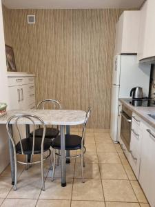 a kitchen with a table and chairs and a refrigerator at Apartamentai Giruliuose - privatus dviejų aukštų namas in Melnragė