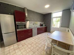 una cucina con armadi rossi e un tavolo di Bienvenue chez Lou a Saint-Aubin-de-Blaye