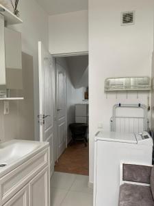 a white bathroom with a sink and a washer at Privatus Apartamentai Akademijoje in Akademija