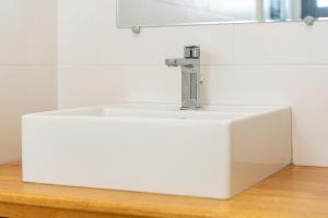 a white sink sitting on top of a wooden counter at Studio Ô Calm - Confort & sérénité, proche aéroport in Saint-Denis +11 photos