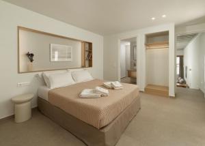 a bedroom with a large bed with towels on it at KYMA Suites Andros in Gavrion