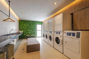a laundry room with washing machines and a green wall at Roomo Transamerica SP Vila Clementino in Sao Paulo