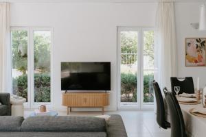 a living room with a flat screen tv and two windows at Villa Melograno by Domus Mirus - Rooftop Cinema, Pool, 6-Minute Walk to Beach in Splitska
