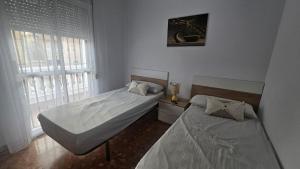 Un dormitorio con dos camas y una ventana. en Camaron Beach House By Sanlúcar Housing, en Chipiona