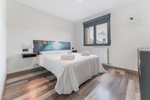 a white bedroom with a bed with two towels on it at Apartamentos Cubicos in Bronchales