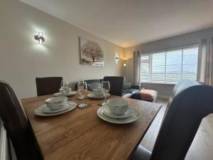 a dining room table with plates and wine glasses at Modern homely well equipped 2BR bungalow next to the racecourse free parking in Hereford