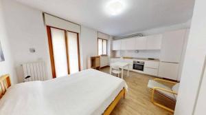 a white bedroom with a large bed and a kitchen at Dreams Home in Locate di Triulzi +8 photos
