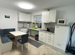 a kitchen with white cabinets and a table and a refrigerator at Ferienwohnung Bergliebe in Füssen