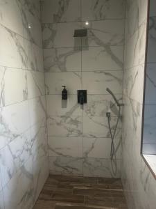 a bathroom with a shower with white marble walls at Chambre chez l habitant Cissac-Medoc in Cissac-Médoc