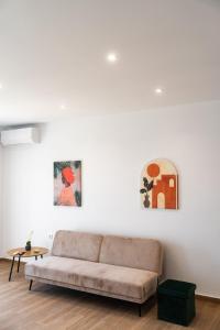 a living room with a couch and two paintings on the wall at Blue Krathis - Luxury Seafront apartments in Paralía Akrátas