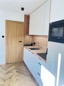 a kitchen with white cabinets and a sink at Apartament Wiosełko in Cieksyn