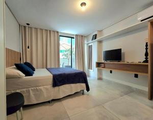 a bedroom with a bed and a desk with a television at Summer by Hosppedar in Ilha da Restinga