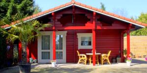 a red house with a table and chairs in front of it at Vakantiewoning Hegga in Hegelsom