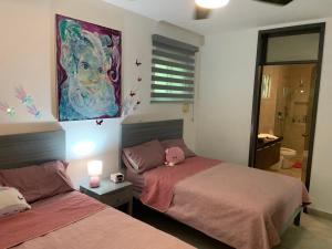 Un dormitorio con dos camas y un cuadro en la pared. en La Escondida 34, en Playa del Carmen