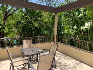 una mesa y sillas en un balcón con árboles en La Escondida 34, en Playa del Carmen