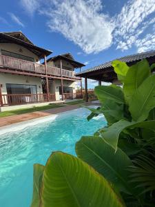 a pool in front of a house with green leaves at Encanto da Barra Pousada in Barra Grande