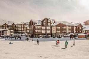 a group of people playing in the snow in front of a building at New Gudauri Loft #1,Room 411, 412 in Gudauri
