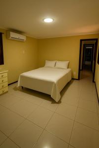 ein Schlafzimmer mit einem weißen Bett in einem Zimmer in der Unterkunft Large Home in Gated Community for COP30, 5 Suites, Event Hall, 450 m2, Perfect for Delegations, Green Ville I in Belém