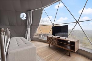 a living room with a flat screen tv in a tent at "Pineview Peak" The Overlook LUX Dome - RRG in Stanton
