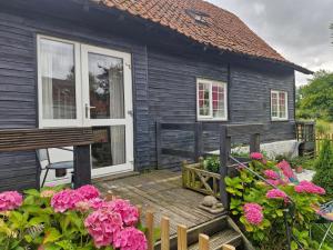 a black house with a wooden deck and flowers at Cosy cottage at rustic escapes 