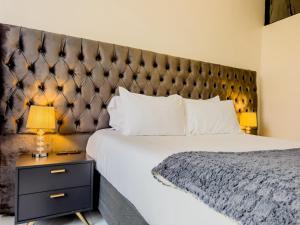 a bedroom with a large bed with a large headboard at Tambarara Manor & Conference Centre in Harare +8 photos