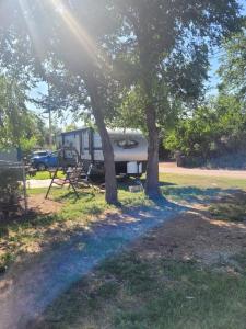 an rv parked under two trees in a field at Cozy Camping in Hot Springs