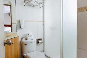 a white bathroom with a toilet and a mirror at Mahia hotel Reñaca in Viña del Mar
