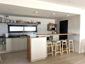 eine Küche mit einer Theke und Hockern darin in der Unterkunft Casa Laura - Casa en Chapa zona Cruz del Sur para 5 PAX - Hola Sur in Chapadmalal