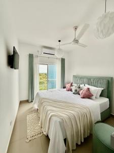 a white bedroom with a large bed with pink pillows at Zeleny Santorini in Negombo